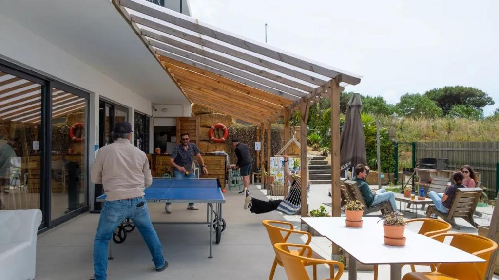 a group of people playing ping pong on a patio at WOT Ericeira Surf Hostel in Ericeira
