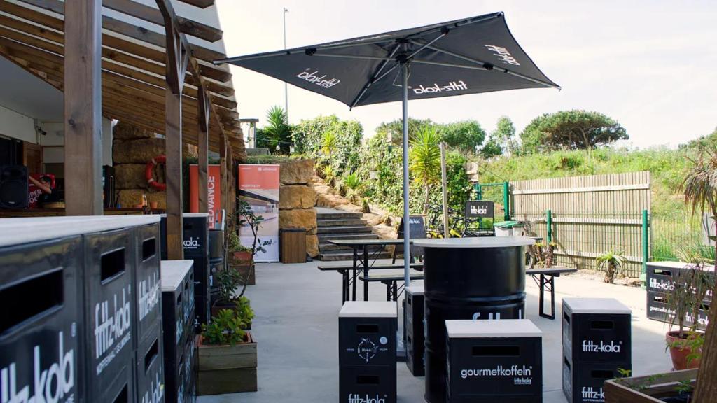 a patio with a table and an umbrella at WOT Ericeira Surf Hostel in Ericeira
