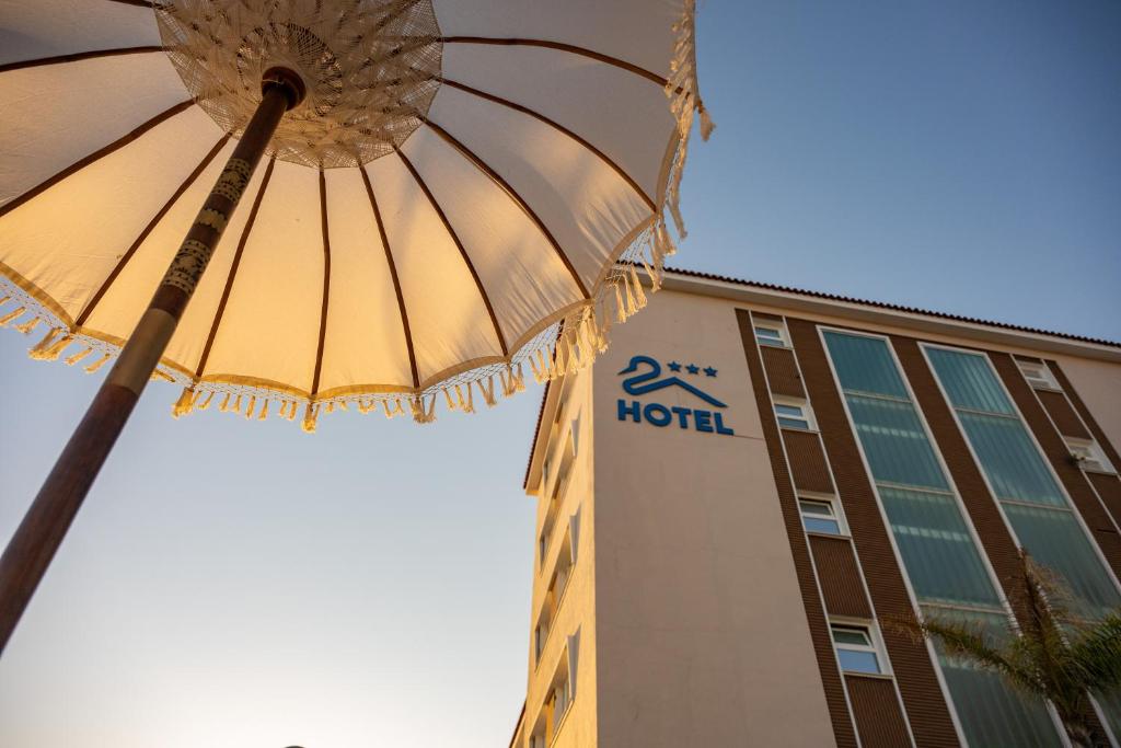 a hotel with an umbrella in front of a building at Pato Rojo in Punta Umbría