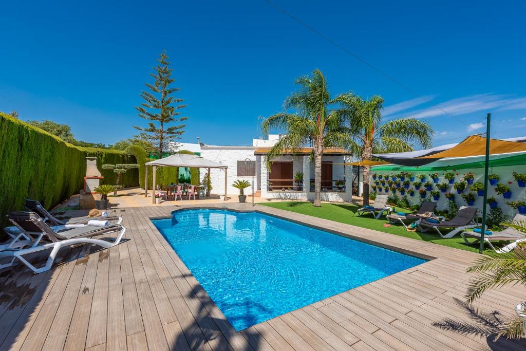 a swimming pool with chairs and a house at Casa Rural Casita de la Cantera in La Lantejuela