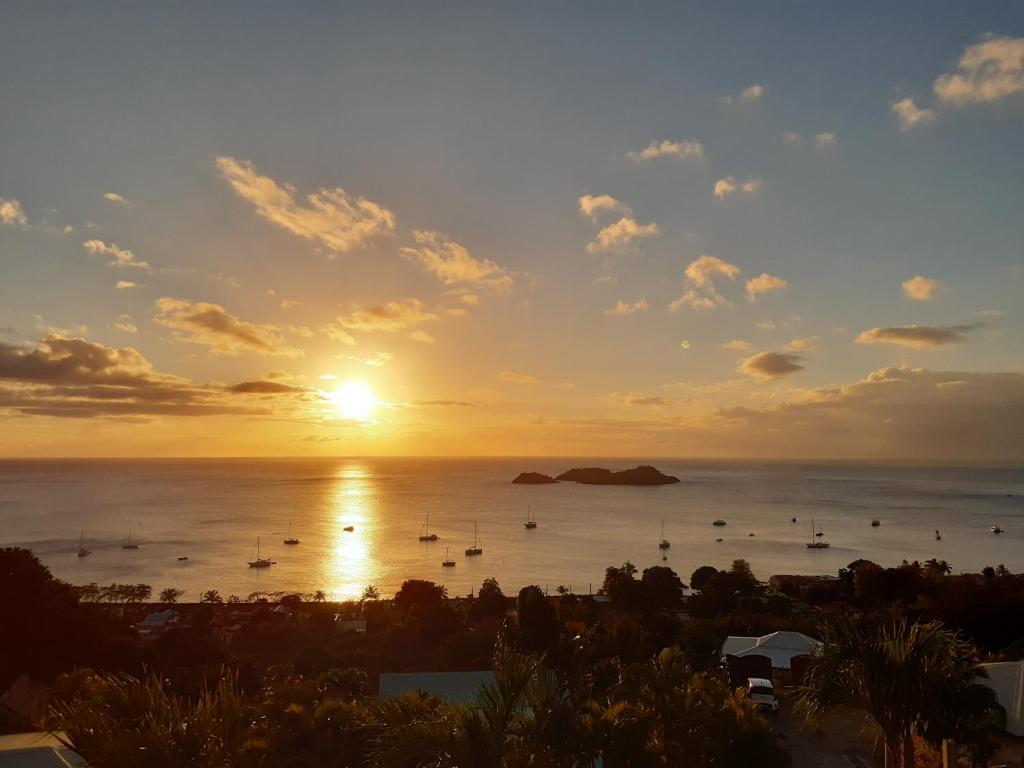 a sunset over the ocean with boats in the water at Logements Vue Mer accès piscine en Guadeloupe in Bouillante