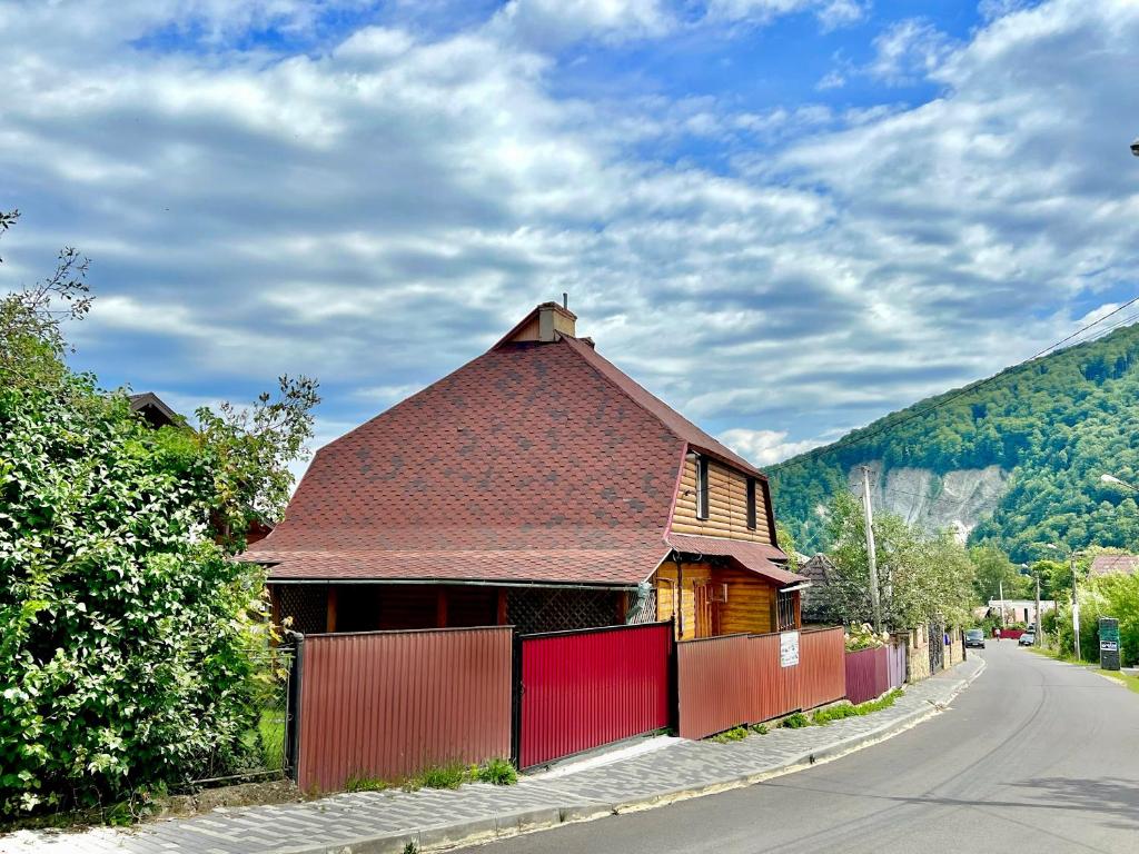 a building with a red fence next to a road at Хатинка in Yaremche