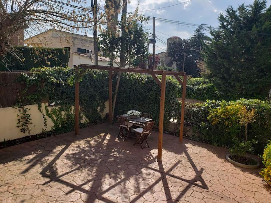 Un patio con una mesa y una pérgola de madera. en Esplendida casa en Valldoreix, en Sant Cugat del Vallès