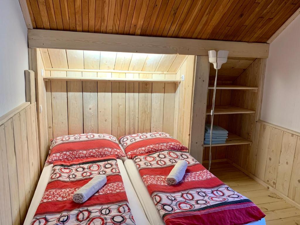 a bed in a small room with a wooden ceiling at Budget izba pre veľkú rodinu alebo skupinu priateľov in ľubochňa
