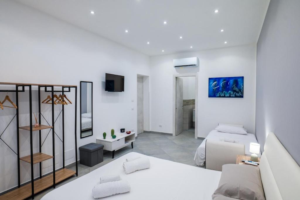 Un dormitorio blanco con una cama y un televisor. en Baron’s Suites, en Palermo