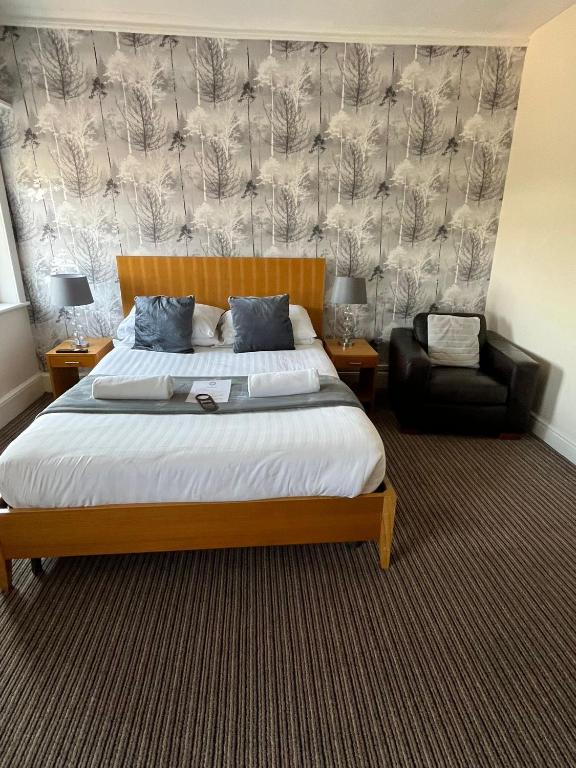 a bedroom with a large bed and a chair at The New Brighton Hotel in New Brighton