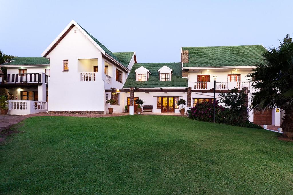 Casa blanca grande con techo verde en A White House Guest House, en Grahamstown