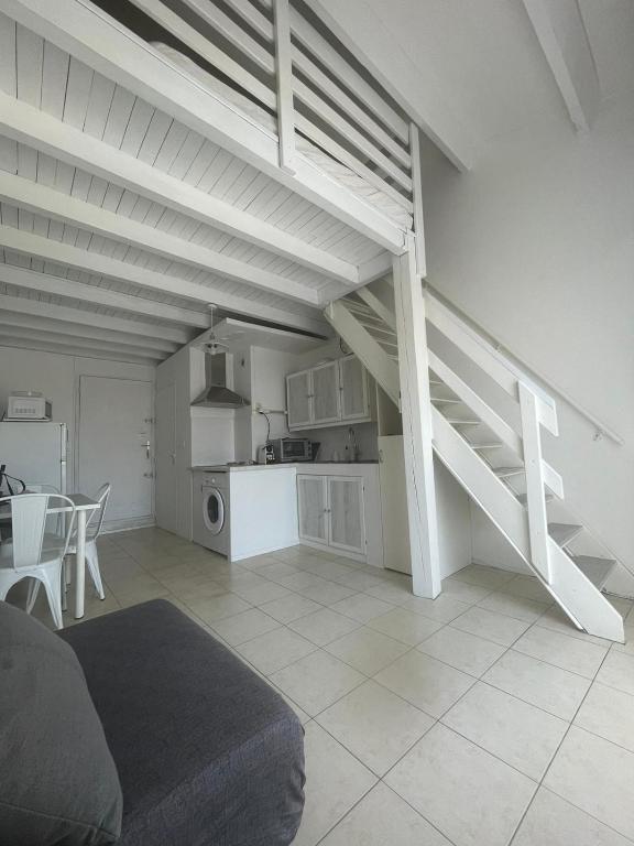 un salon avec un escalier et une cuisine dans l'établissement Studio mezzanine 32 m2 Port La Nouvelle Quartier des Lacs proche plage, à Port-la-Nouvelle