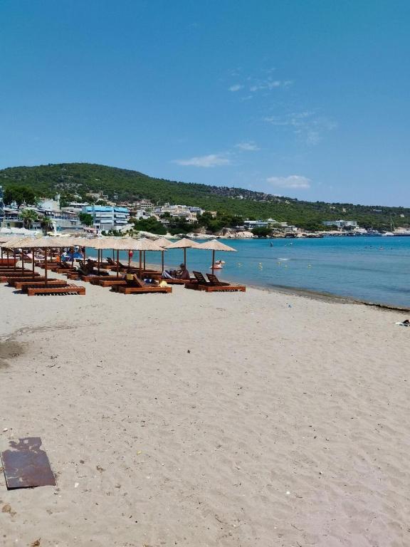 a beach with chairs and umbrellas on the sand at Nikolas Marios by Frangki in Agia Marina Aegina