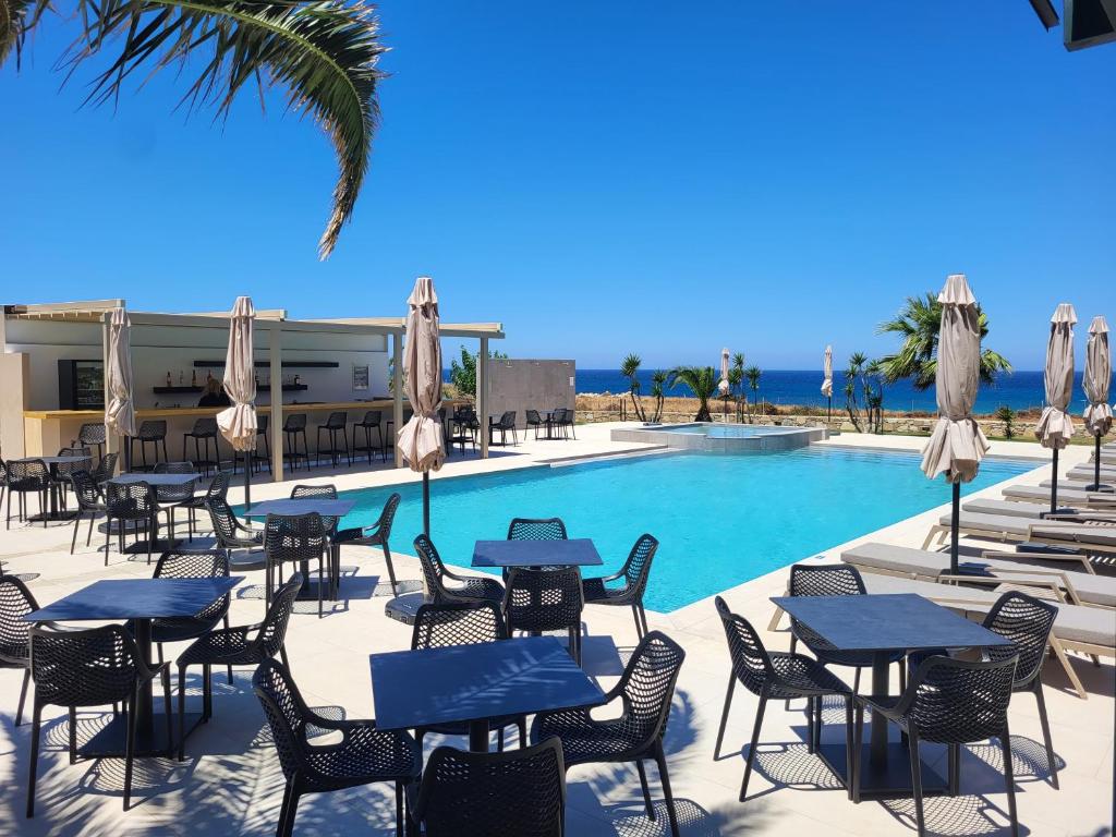 a patio with tables and chairs next to a swimming pool at Pachia Ammos Falasarna in Falasarna