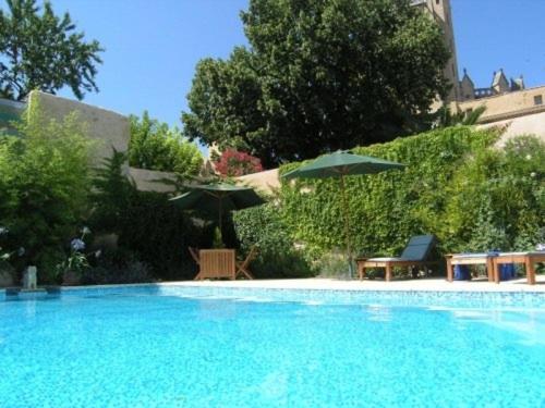 a large blue swimming pool with an umbrella and chairs at OCC34 - Capestang - Villa Quinlan in Capestang