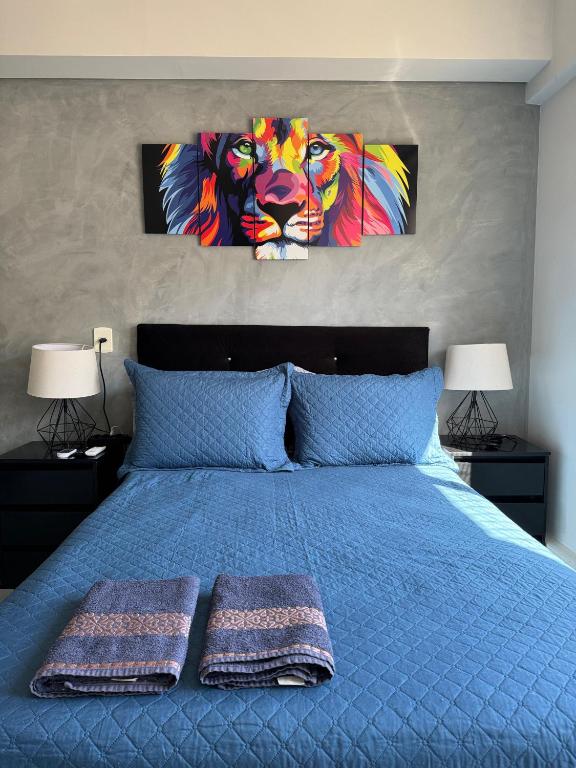 a bedroom with a blue bed with two paintings of a lion at Studio completo e aconchegante in Ribeirão Preto