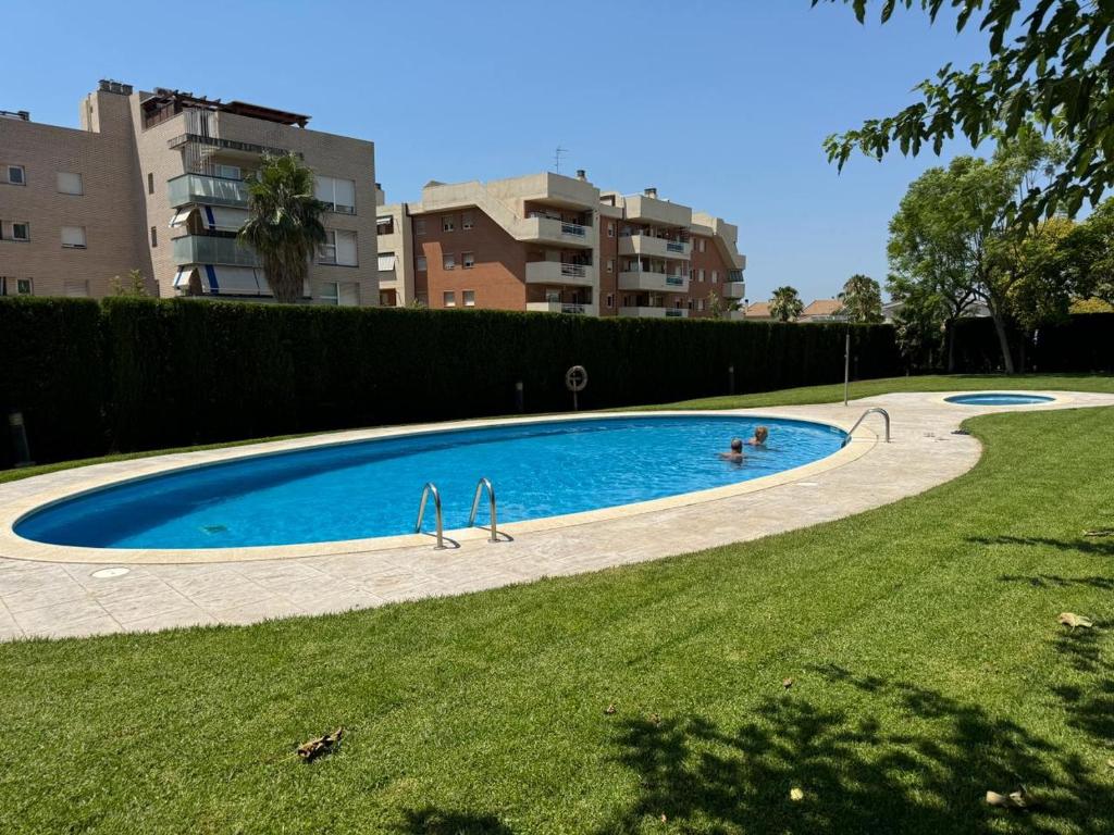 a swimming pool with two people in the grass at Lindo piso residencial en salou centrico in Salou