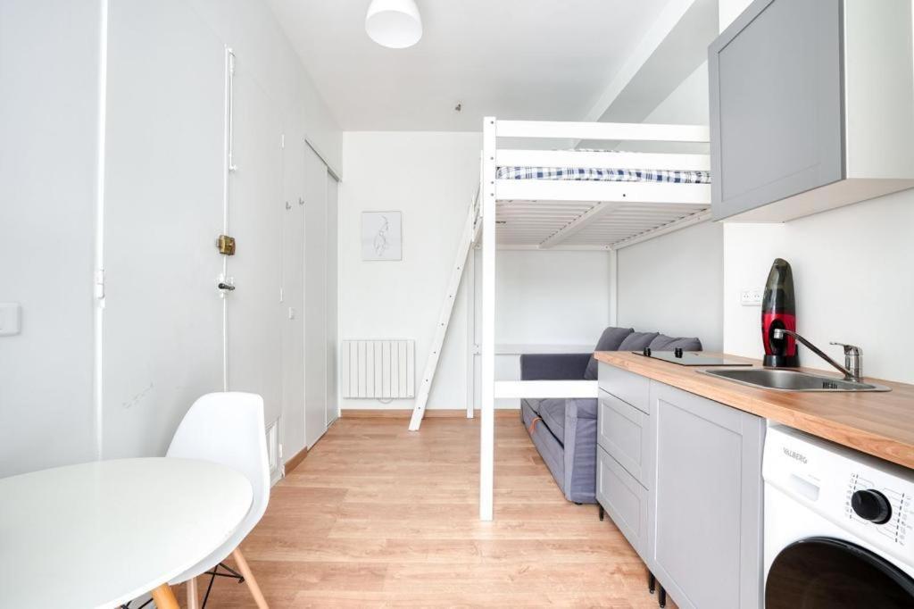 - une cuisine avec des placards blancs, un évier et une table dans l'établissement Le Studio Champs Elysées, à Paris