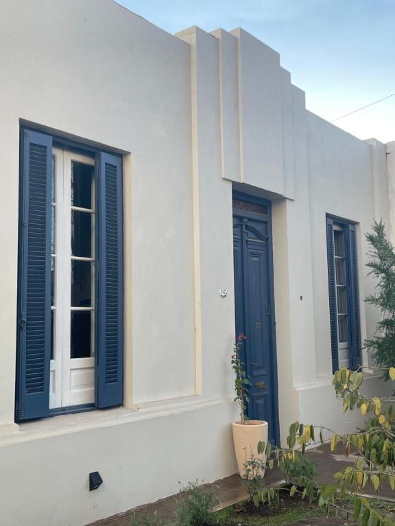 un bâtiment blanc avec des portes et des plantes bleues dans l'établissement Casa de pueblo, à Cañada Rosquín