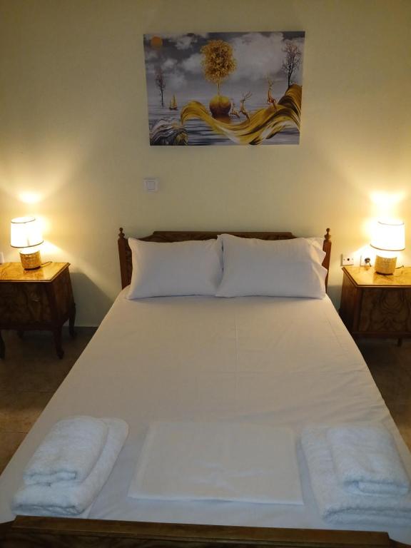 a white bed with two lamps on two tables at Ελένης apartment in Gythio