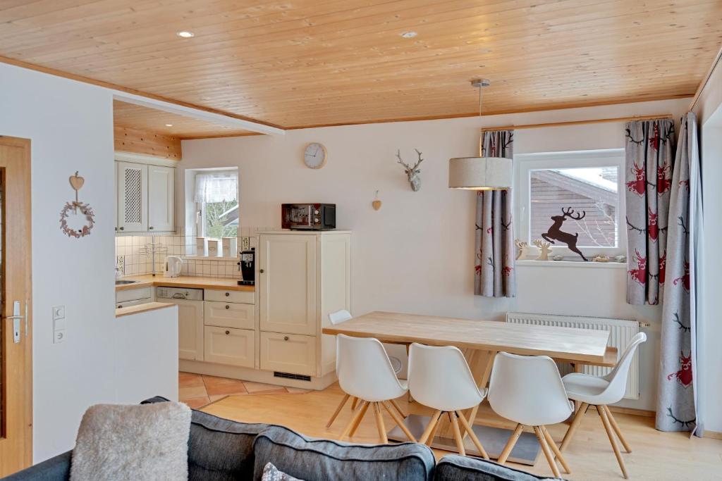 a kitchen with a wooden table and white chairs at Haus Klinsterwald in Sankt Oswald
