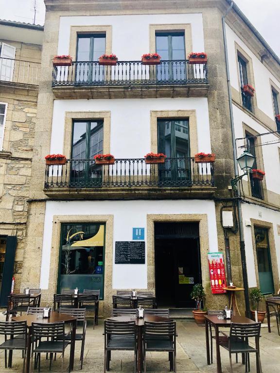 a building with tables and chairs in front of it at Hotel Arco de Mazarelos in Santiago de Compostela