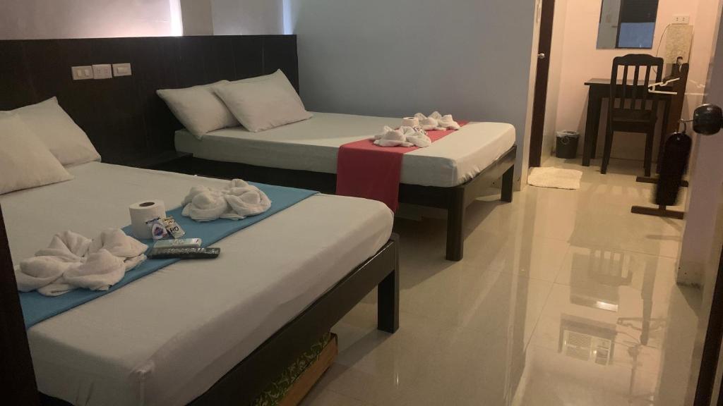 een kamer met 2 bedden en een tafel met handdoeken bij Anang Balay Turista in El Nido