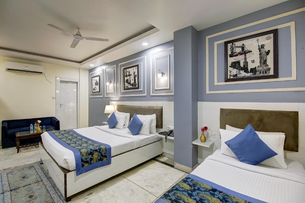 2 camas en un dormitorio con paredes azules y blancas en OPO Essential SKYNEX AEROCITY,Free airport Pickup and Drop, en Nueva Delhi