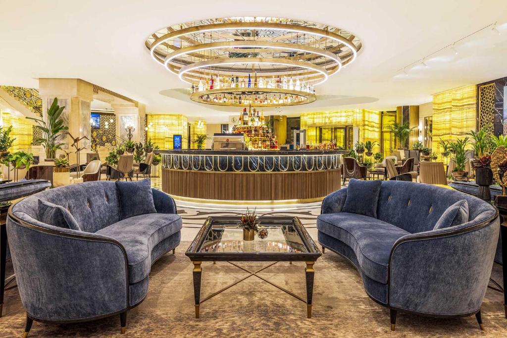a lobby with two blue chairs and a chandelier at CVK Park Bosphorus Hotel Istanbul in Istanbul