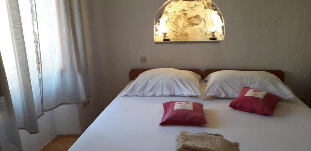 a white bed with two red pillows on it at Dora in Kraljevica