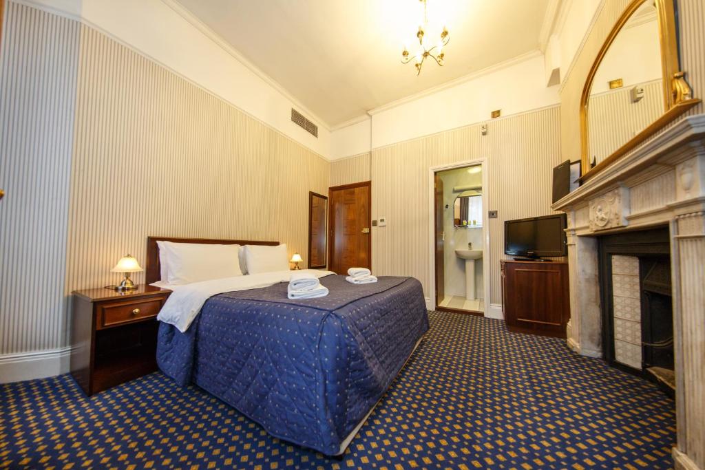 倫敦的住宿－攝政大樓酒店，酒店客房配有一张床和一个壁炉。