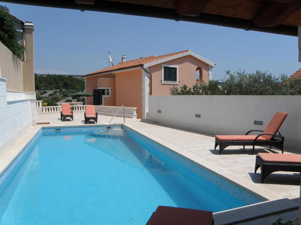 uma piscina com duas cadeiras e uma casa em Villa Marica Primošten em Primošten