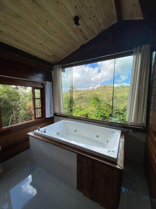 a large bath tub in a room with a window at Encanto da Mata - Chalé Ipê - Lavras Novas-MG in Lavras Novas