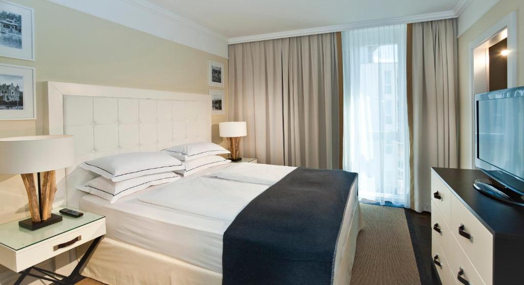a hotel room with a large bed and a television at Lake's in Pörtschach am Wörthersee