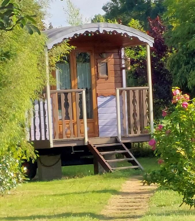une cabane en bois dans un jardin avec un kiosque dans l'établissement Les roulottes de la Brauderie, à Les Varennes