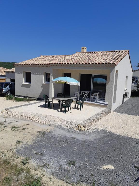 a house with a patio with a table and an umbrella at villa soleil in Ruoms