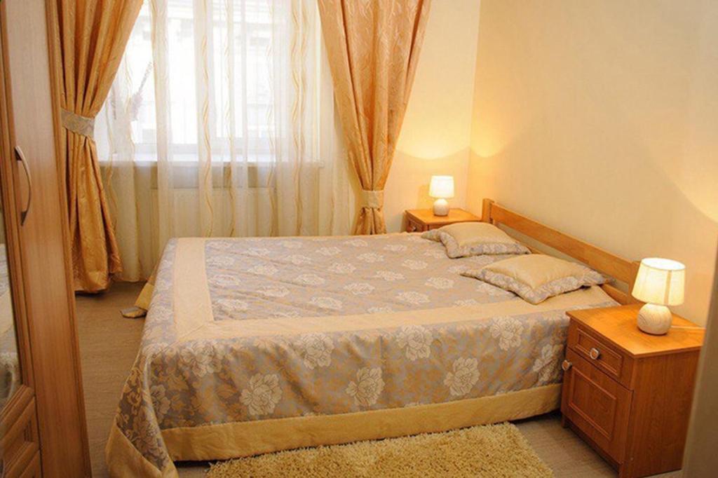 een slaapkamer met een bed met 2 lampen en een raam bij Anna Apartments in Lviv