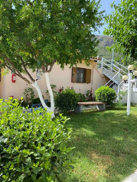 una casa con un albero e una panchina nel cortile di Garden Rooms a Himare