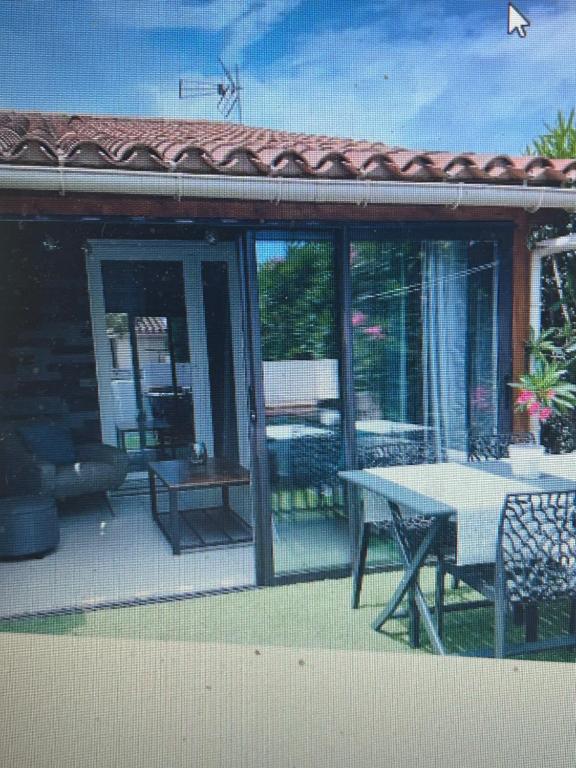 eine abgeschirmte Veranda mit einem Tisch und einer Terrasse in der Unterkunft saint cyprien in Saint-Cyprien