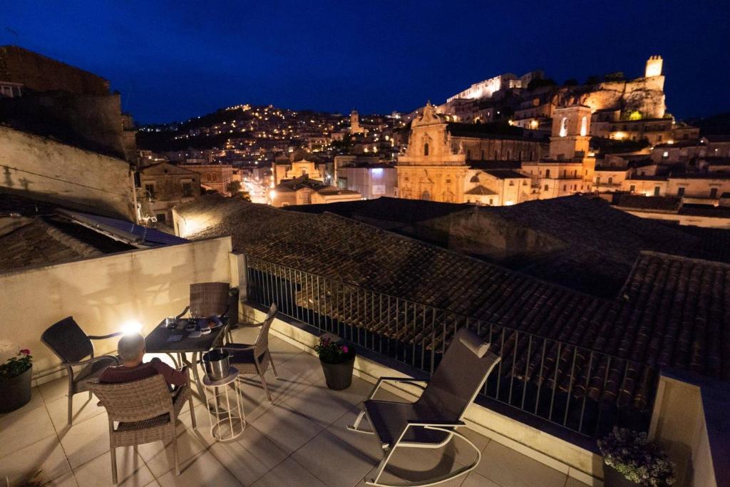balkon z krzesłami i widokiem na miasto w nocy w obiekcie Le Magnolie Hotel w mieście Modica