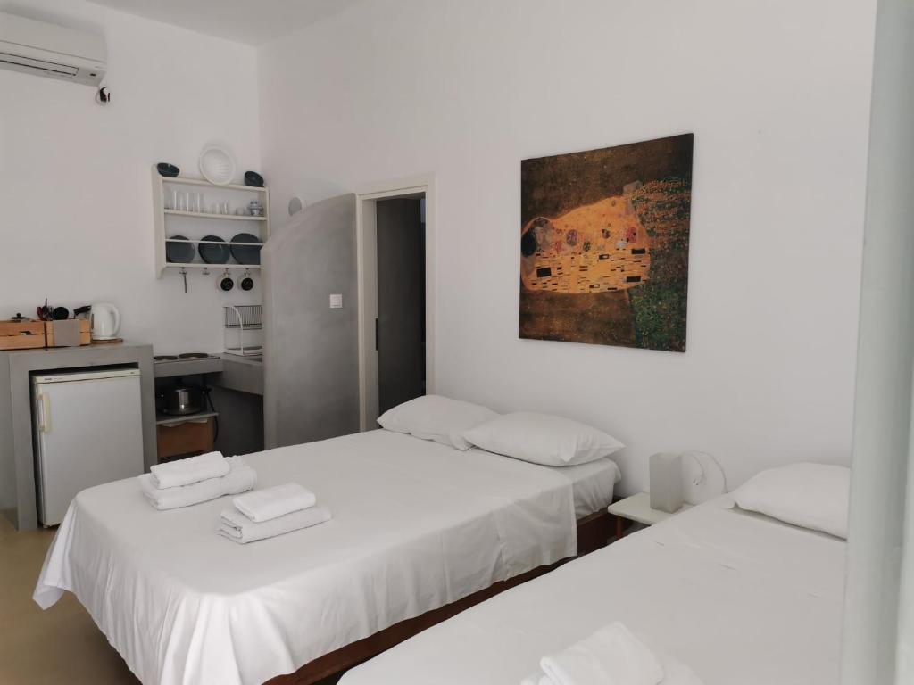 a white room with two beds and a kitchen at Thalassa3 in Andros