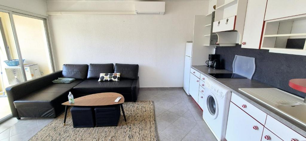 un salon avec un canapé et une table dans une cuisine dans l'établissement F1 Cosy 45m2, 2 mn mer, du port, cœur ville, à La Grande Motte