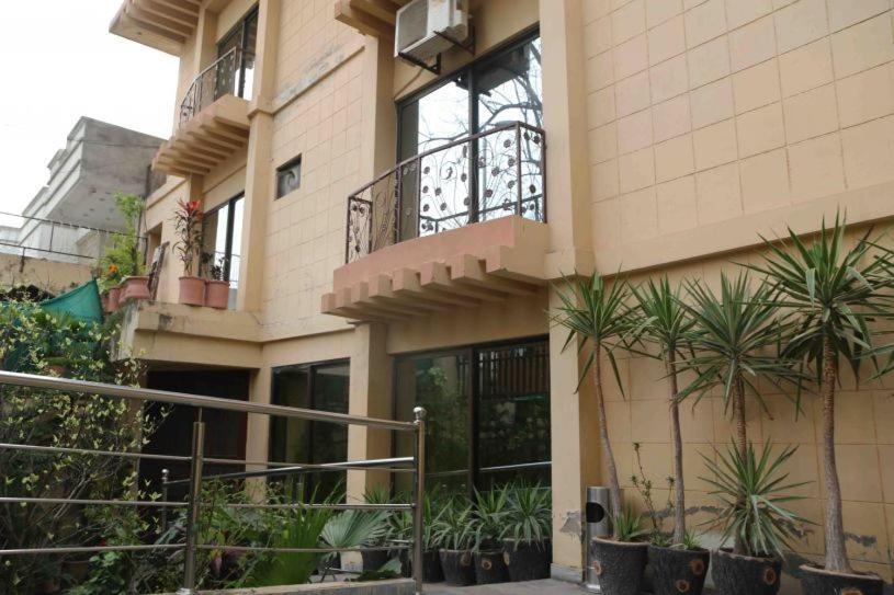 um edifício com varanda e plantas em frente em Savoy Inn Guest House Islamabad em Islamabad