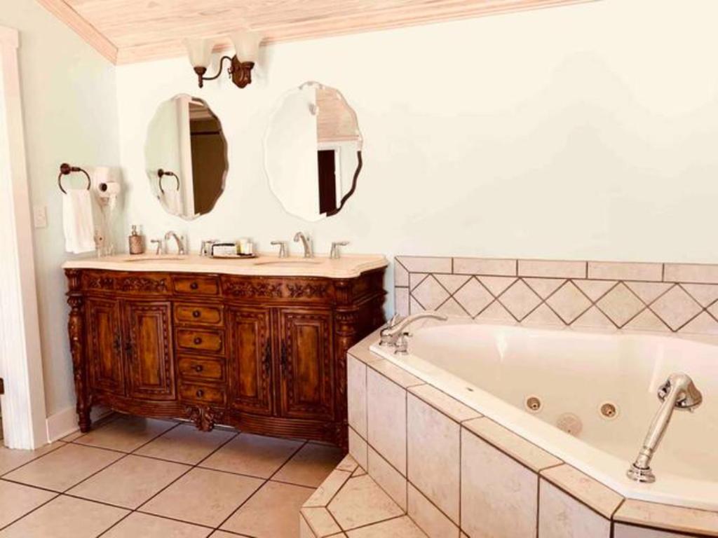 bagno con vasca, lavandino e specchio di Emigrant's Inn a Fredericksburg
