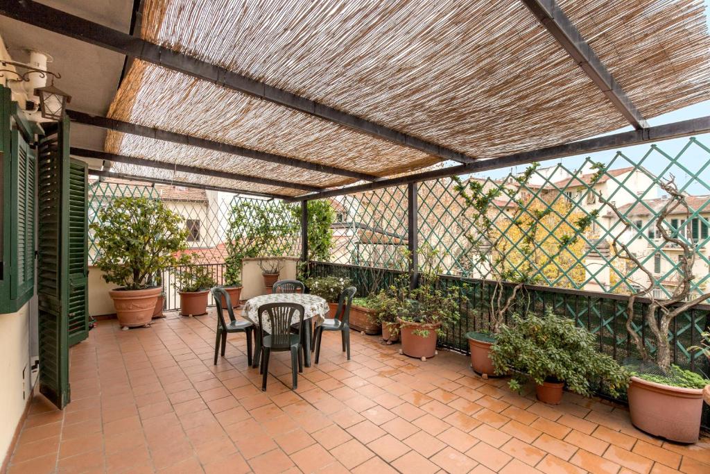 eine Terrasse mit einem Tisch, Stühlen und Topfpflanzen in der Unterkunft Appartamento Cittadella 39 in Florenz