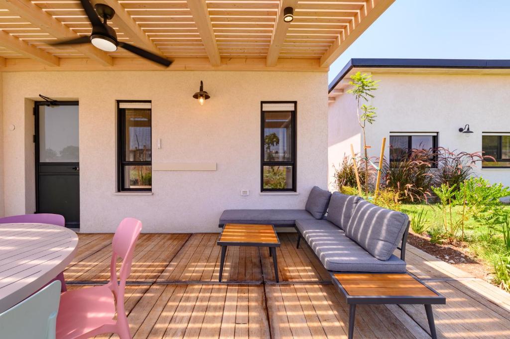 a patio with a blue couch and a table and chairs at צימרים למשפחות, אירוח ~כימים אחדים~ משק אביגור-מקובר in Giv'at Yo'av