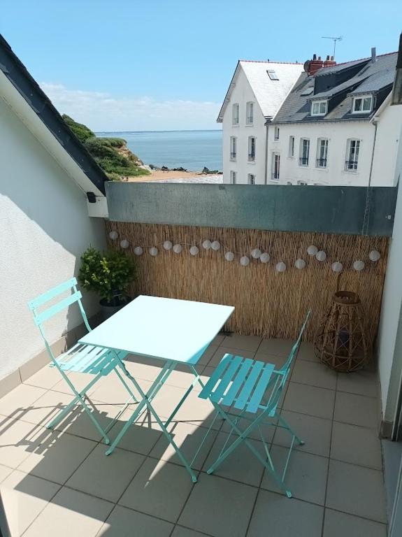 d'une table et de deux chaises sur un balcon donnant sur l'océan. dans l'établissement St-Marc T3 face mer à 20m de la plage, à Saint-Nazaire