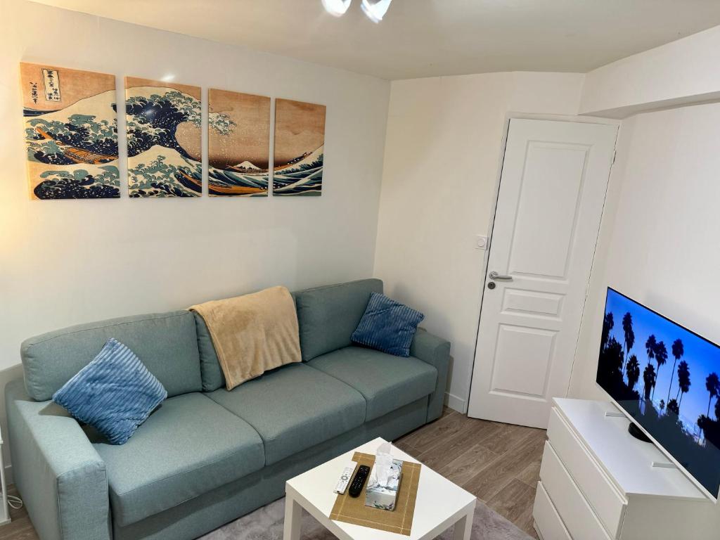 un salon avec un canapé bleu et une table dans l'établissement Studio Cozy au cœur des Carmes, à Toulouse