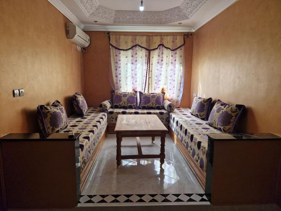 a living room with a long couch and a table at Logement climatisé proche de Fès in El Harmiine