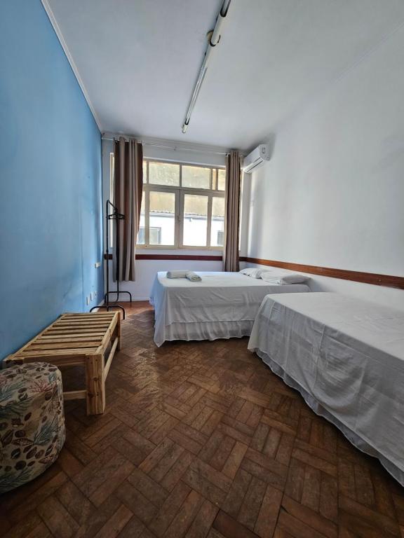 a room with two beds and a bench and a window at Nomads Hostel Multicultural & Coworking in Salvador
