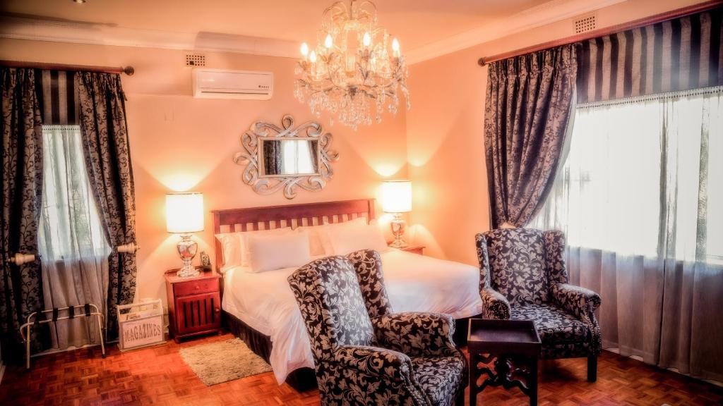 - une chambre avec un lit, deux chaises et un lustre dans l'établissement Nauntons Guest House & Wedding Venue, à Ladysmith