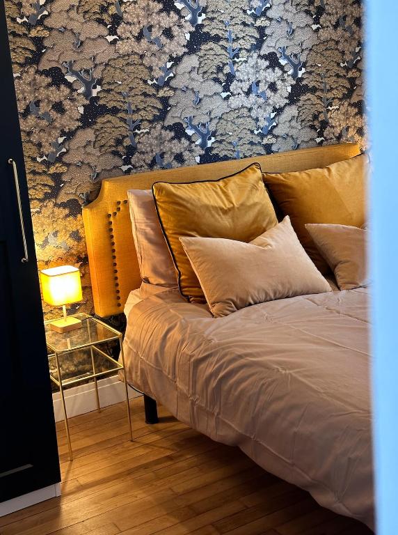 Cette chambre comprend un lit avec des oreillers et un mur fleuri. dans l'établissement Appartement - Triangle d'or - Vue Capucins, à Brest
