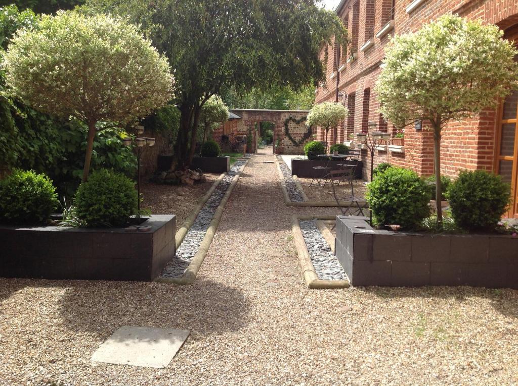 um jardim com árvores e arbustos em frente a um edifício em B&B Le Fond de la Cour em Honfleur