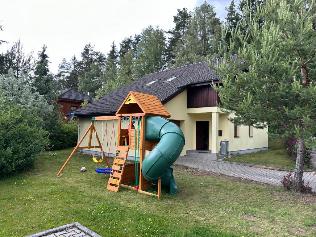 a house with a playground with a slide in the yard at Villa Park Lipno 208 in Lipno nad Vltavou